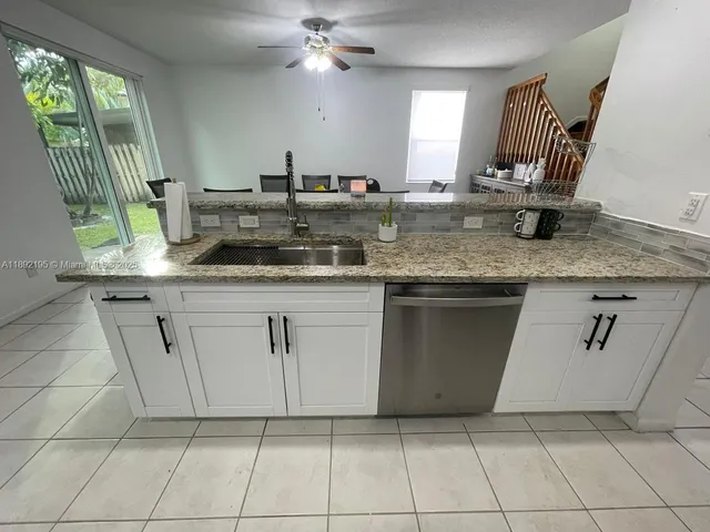 a kitchen with granite countertop white cabinets white appliances a sink and a mirror