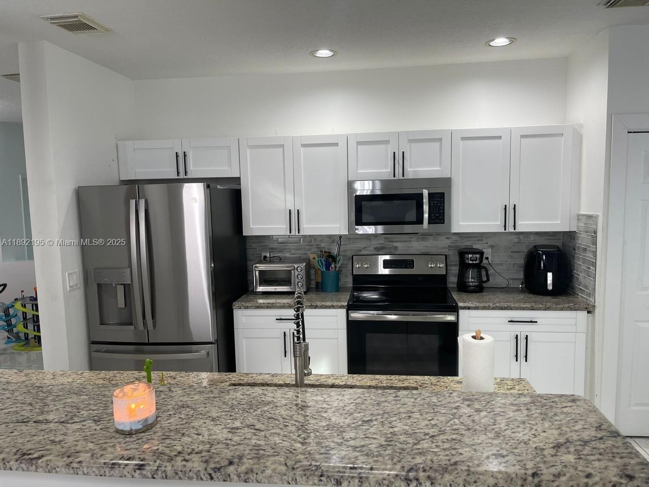 10470 Southwest 16th Street Pembroke Pines, FL 33025 - Photo 8 of 26 a kitchen with stainless steel appliances granite countertop a refrigerator stove a sink and a microwave