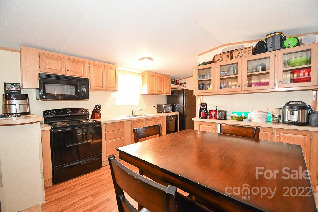 1426 Clontz Long Road Monroe, NC 28110 - Photo 7 of 12 a kitchen with stainless steel appliances a stove a sink dishwasher a refrigerator with a dining table and chairs with wooden floor