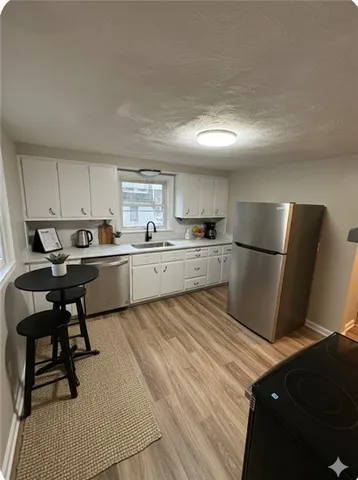 a kitchen with a sink a refrigerator and chairs