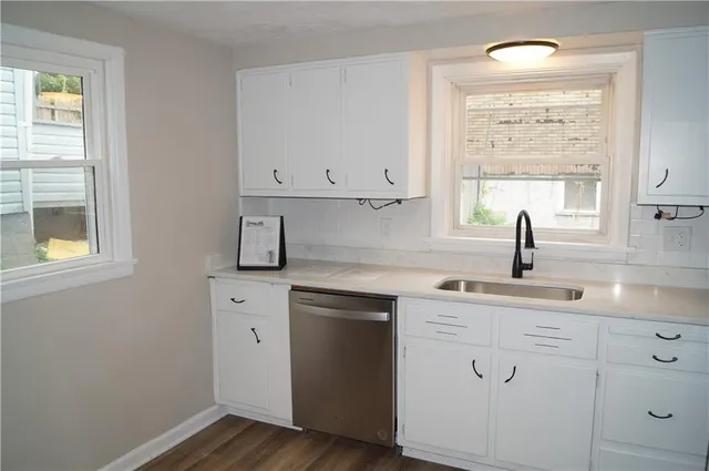 a kitchen with white cabinets a sink and a window