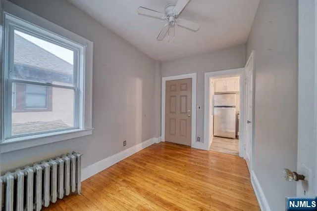 a view of empty room with wooden floor and fan