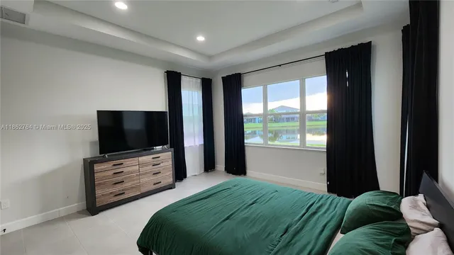 a bedroom with a bed and a flat tv screen on dresser