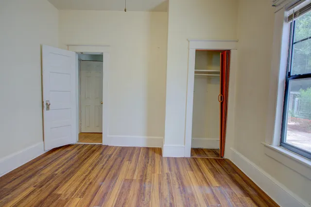 an empty room with wooden floor and windows