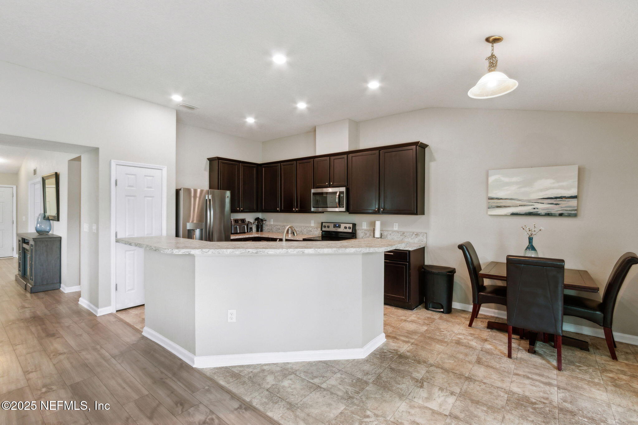 7197 Steventon Way Jacksonville, FL 32244 - Photo 16 of 58 a kitchen with stainless steel appliances kitchen island granite countertop a refrigerator a stove a sink a dining table and chairs