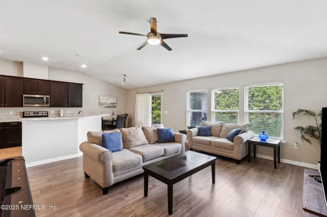 a living room with furniture kitchen view and a wooden floor