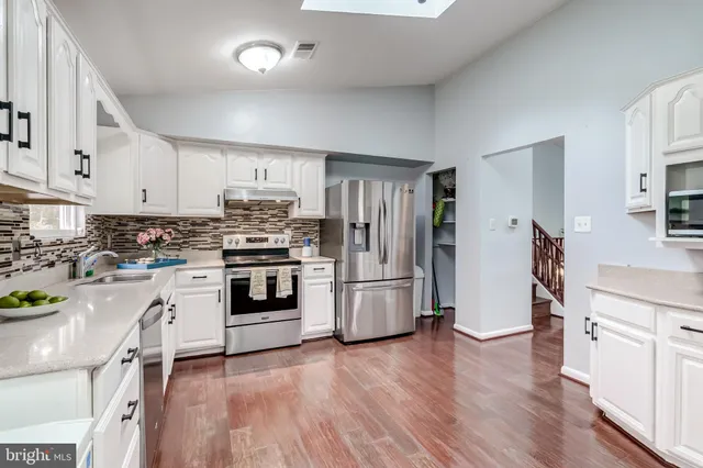 a kitchen with granite countertop white cabinets and stainless steel appliances