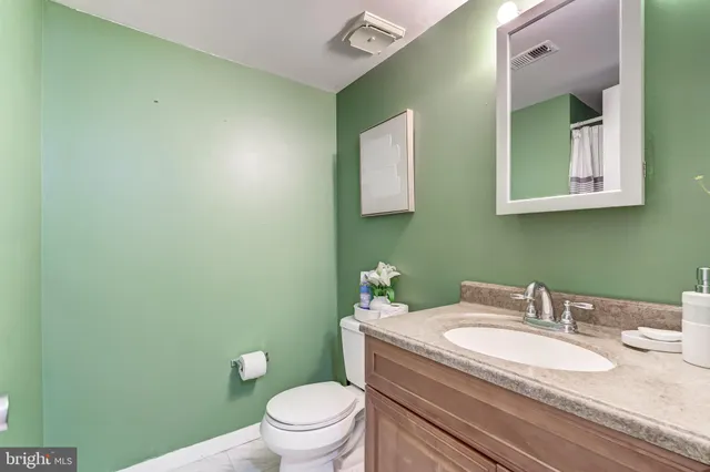 a bathroom with a granite countertop toilet sink and mirror