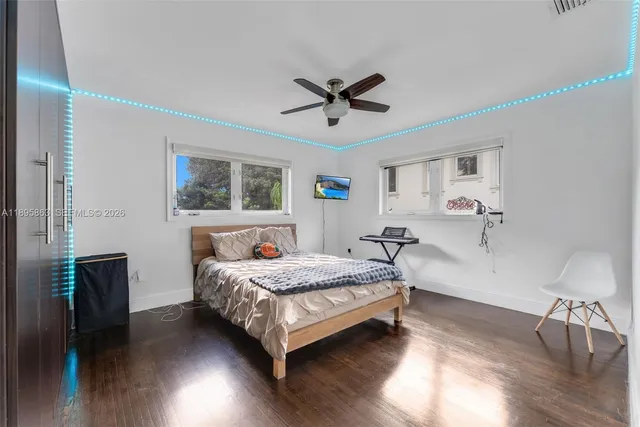 a bedroom with a bed a table and wooden floor