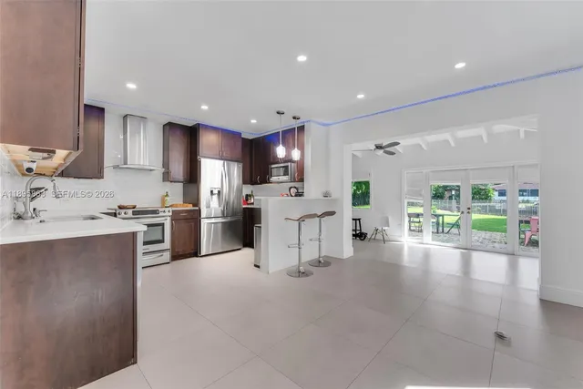 a kitchen with stainless steel appliances kitchen island granite countertop a refrigerator oven a sink dishwasher and white cabinets with wooden floor
