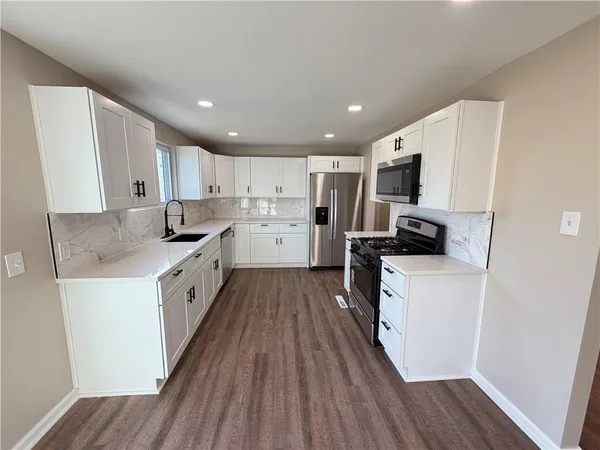 a kitchen with refrigerator a microwave a stove a sink dishwasher and wooden cabinets with wooden floor