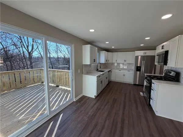 a kitchen with stainless steel appliances wooden floor and a window