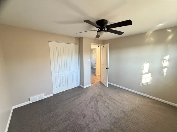 an empty room with windows and fan