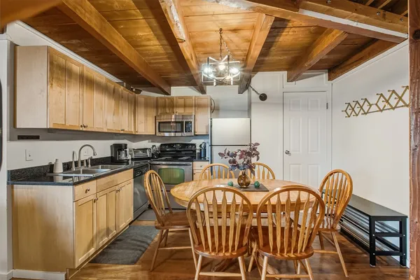 a kitchen with stainless steel appliances granite countertop a sink a stove a refrigerator cabinets a dining table and chairs