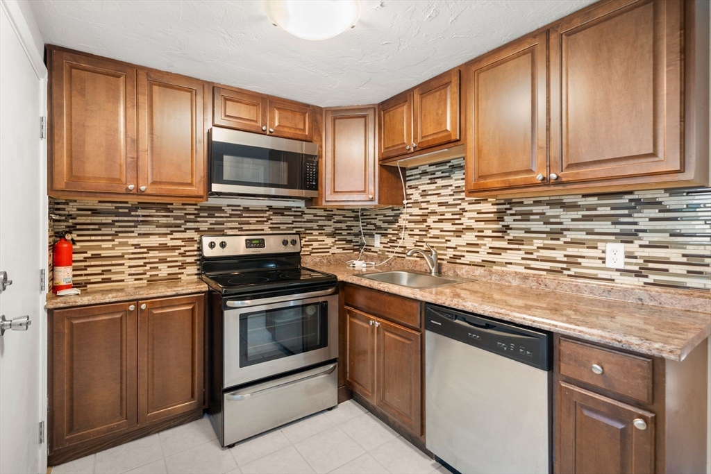 9 Tideview Path, Unit 10 Plymouth, MA 02360 - Photo 1 of 9 a kitchen with stainless steel appliances granite countertop a stove a sink and a microwave