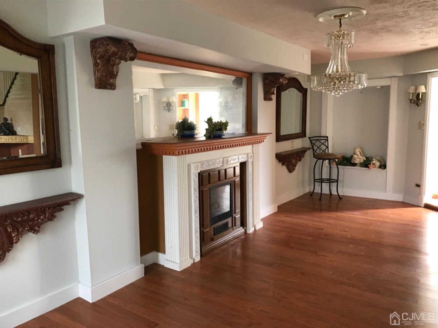 25 Wilshire Road Edison, NJ 08817 - Photo 2 of 18 a view of a livingroom with a fireplace a chandelier and wooden floor