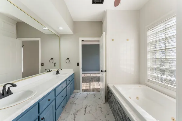 a bathroom with a tub sink double vanity granite and shower