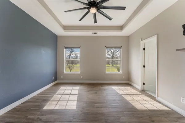 a view of empty room with wooden floor and fan