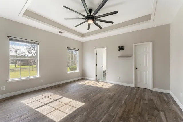 a view of an empty room with wooden floor and windows