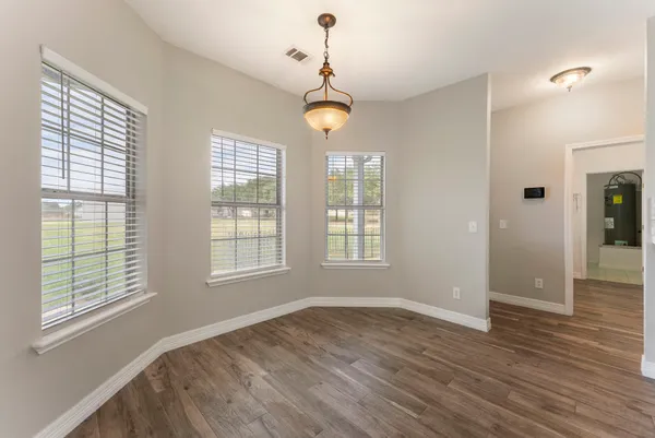 a view of an empty room with wooden floor and windows