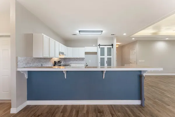 a kitchen with stainless steel appliances granite countertop a sink cabinets and wooden floor