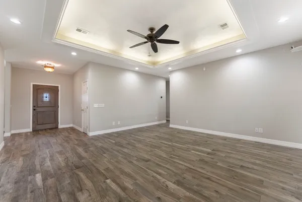 an empty room with wooden floor and a ceiling fan