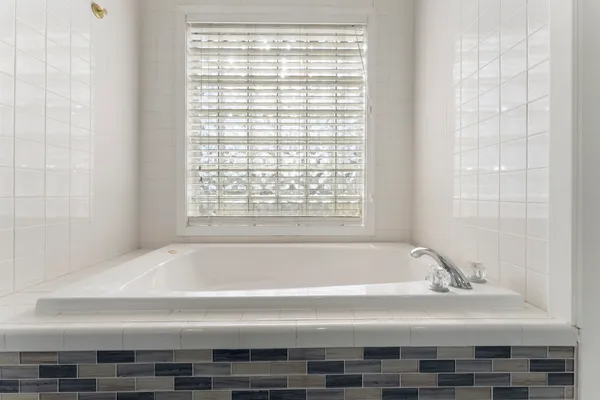 a bathroom with bathtub and next to a window