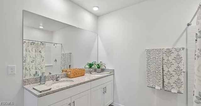 a bathroom with a granite countertop sink a mirror and shower