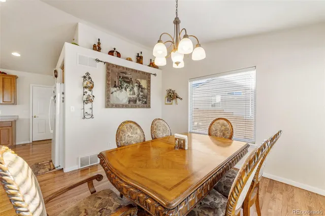 a dining room with wooden floor a chandelier a wooden table and chairs