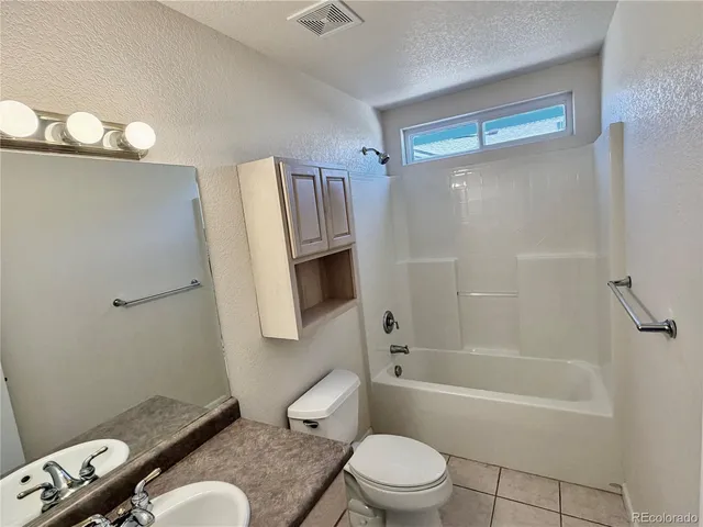 a bathroom with a granite countertop bathtub sink vanity mirror and toilet