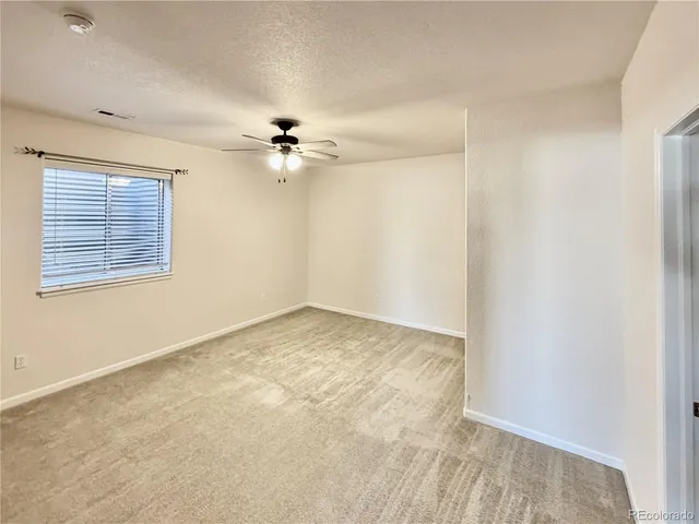 an empty room with windows and fan