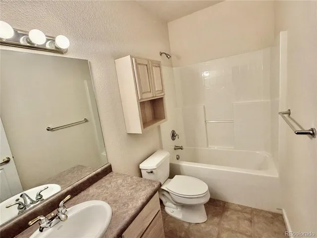 a bathroom with a granite countertop toilet sink and mirror
