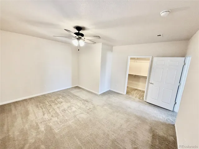 an empty room with closet and a ceiling fan