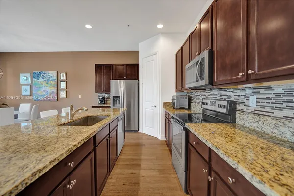 a kitchen with stainless steel appliances granite countertop a sink a stove and a refrigerator