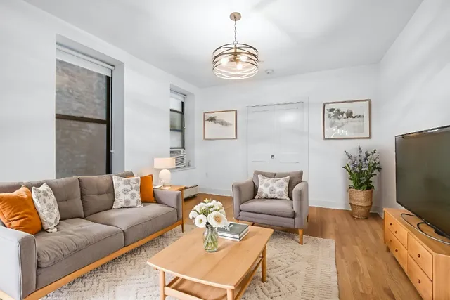 a living room with furniture a flat screen tv and a chandelier