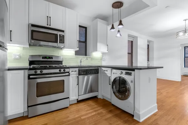 a kitchen with stainless steel appliances granite countertop a sink a stove a microwave and wooden cabinets