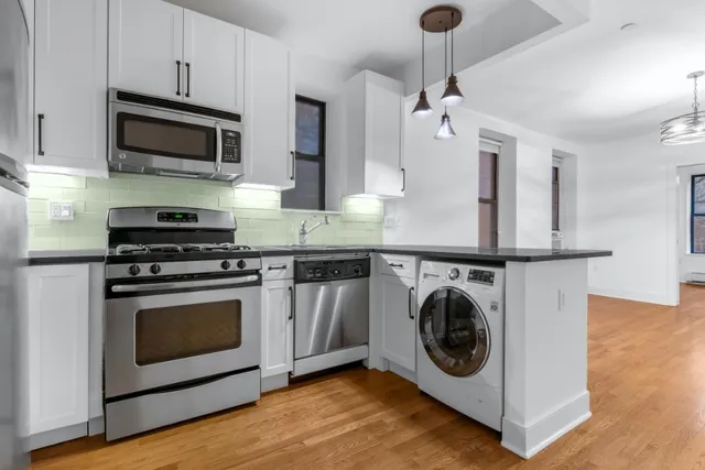 a kitchen with stainless steel appliances granite countertop a sink a stove a microwave and wooden cabinets