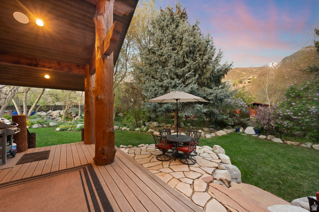 10280 Dimple Dell Road Sandy, UT 84092 - Photo 19 of 58 Deck at dusk with a yard, outdoor dining space, a patio area, a mountain view, and a grill