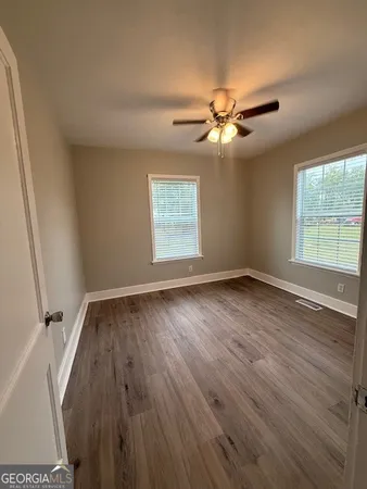 a view of empty room with wooden floor and fan