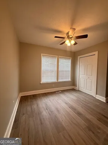 a view of an empty room with window and wooden floor