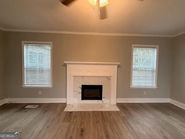 an empty room with wooden floor fireplace and windows