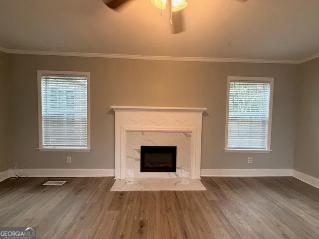 an empty room with wooden floor fireplace and windows