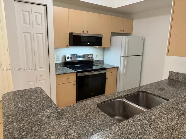 a kitchen with stainless steel appliances granite countertop a sink stove and refrigerator