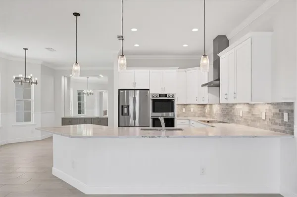 a large kitchen with kitchen island a large counter top a sink stainless steel appliances and cabinets
