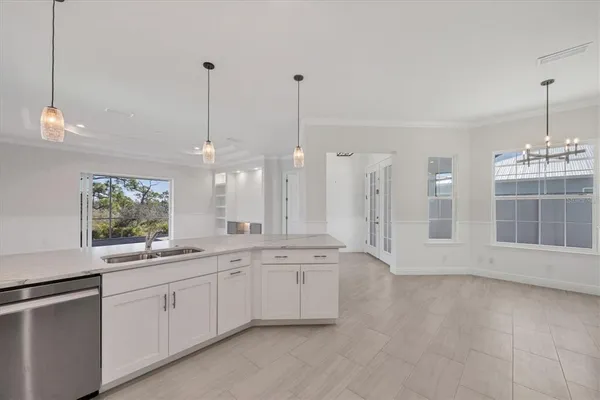 a large white kitchen with a sink a window and stainless steel appliances