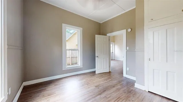 an empty room with wooden floor and windows