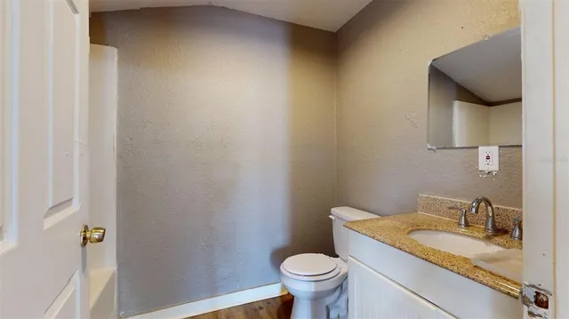 a bathroom with a granite countertop sink and a toilet