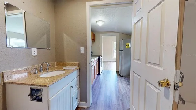 a bathroom with a granite countertop sink a mirror and a refrigerator