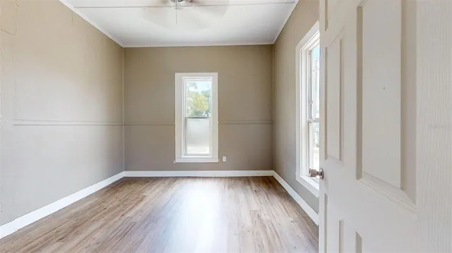 an empty room with wooden floor and windows