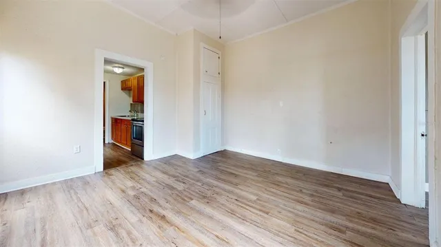 a view of an empty room with wooden floor and closet